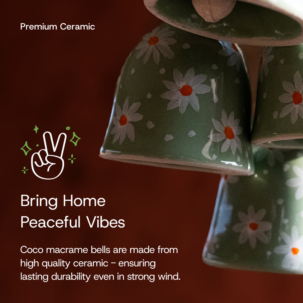 Green ceramic macrame bells with white daisy patterns hanging together on a macrame string.