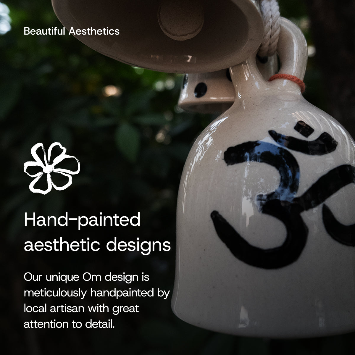 White ceramic bell with black Om symbol, hanging against a dark background.
