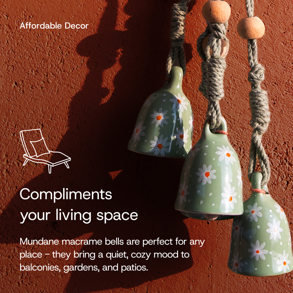 Decorative ceramic bells with floral patterns hanging against a red-brown wall.