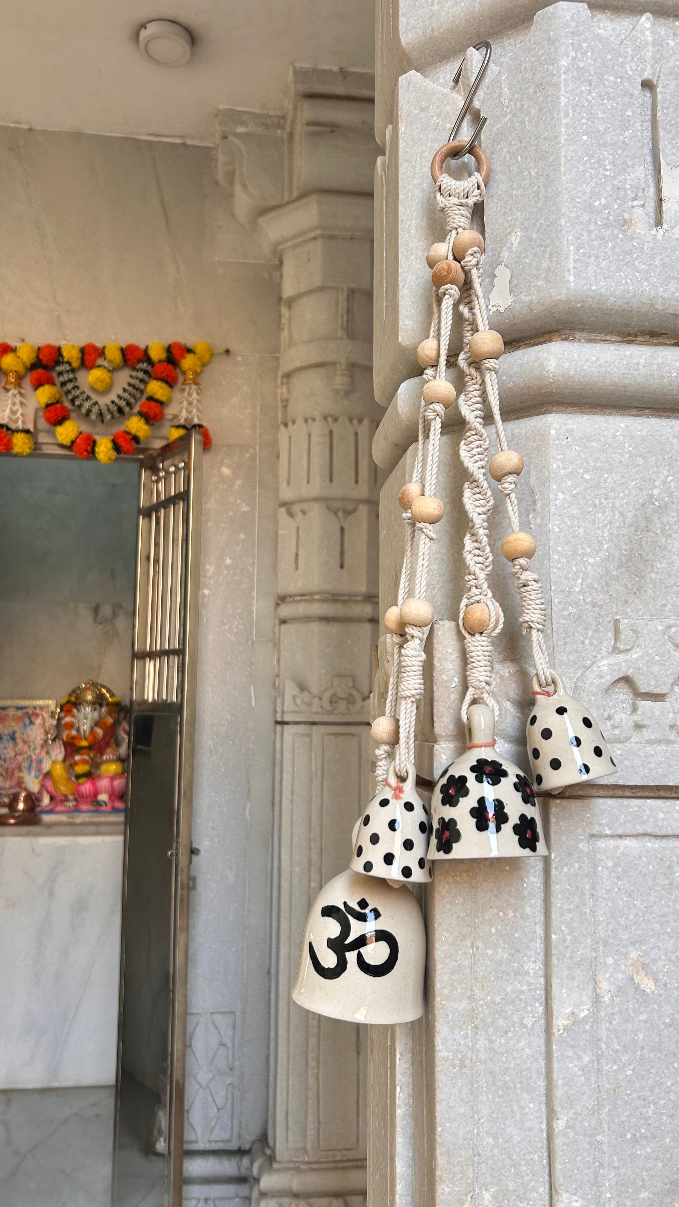 Decorative bells with Om symbol hanging on a stone wall.